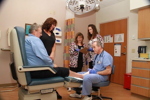 As nurses from the Center for Wound Management Annette Necciai and Toni McNett (left to right) review the patient’s chart, Michael and Dana Gottke watch as Dr. Gene Manzetti conducts a follow up exam.