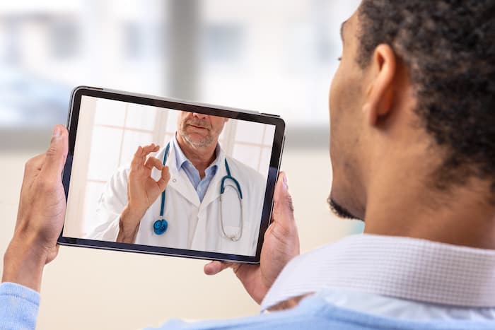 Telemedicine and health care concept with a young man and a doctor on computer screen