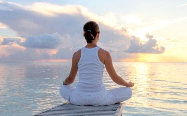 a lady meditating by the water on her vacation
