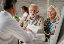 Happy mature couple informing themselves about health insurance while talking to a doctor at clinic.
