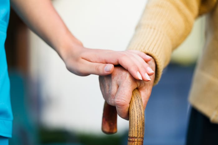 Doctor holding a senior patiens 's hand on a walking stick - special medical care concept for Alzheimer 's syndrome.