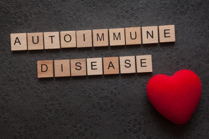 The word autoimmune disease formed with wooden letters and a heart on dark background