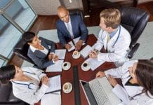 Interracial group of business men & women, businessmen and businesswomen and doctors team meeting in hospital boardroom