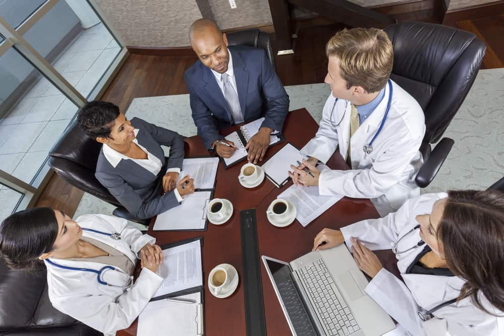 Interracial group of business men & women, businessmen and businesswomen and doctors team meeting in hospital boardroom