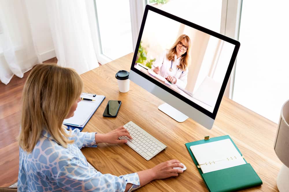 Shot of middle aged woman using a computer to make a video call with her female doctor.