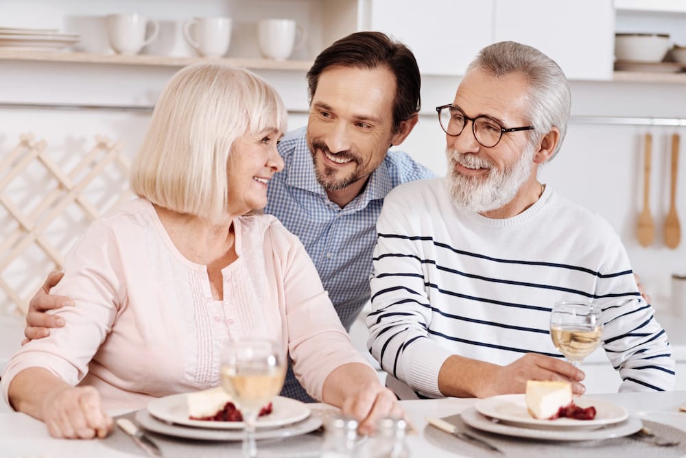 Thanking my parents for everything . Smiling careful handsome man having dinner and enjoying time with his senior parents while expressing love to them