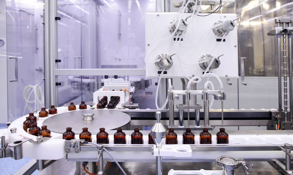 Bottles on the bottling line of a pharmaceutical plant. A machine with a lot of tubing fills the bottles.