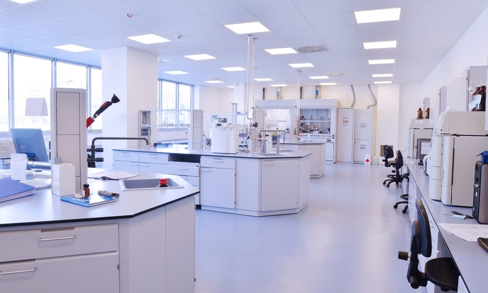 Modern lab with white walls and white furniture equipped with different machines and bright overhead lights.