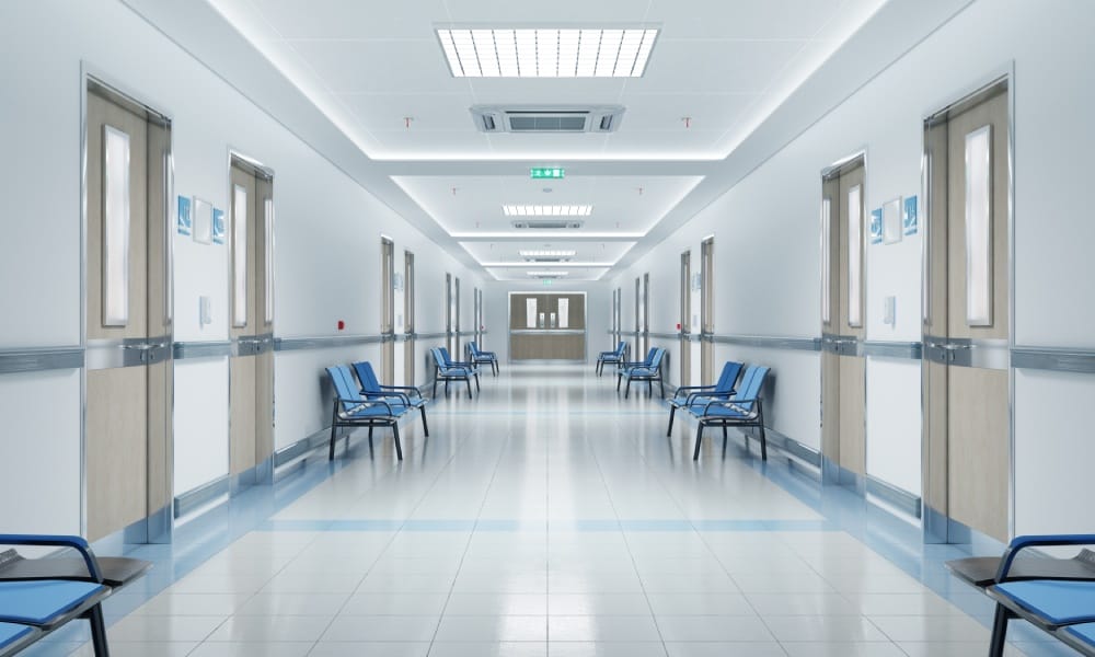 An interior view of what appears to be a hallway in a healthcare facility that is lined with chair and doors.
