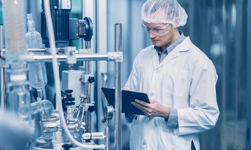 A medical doctor is in a laboratory and is using a tablet to inspect the results from the scientific machine.
